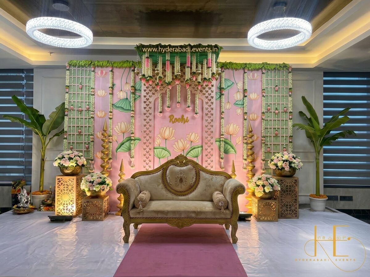 Premium pink floral naming ceremony stage decoration with lotus backdrop, hanging florals and royal sofa seating.