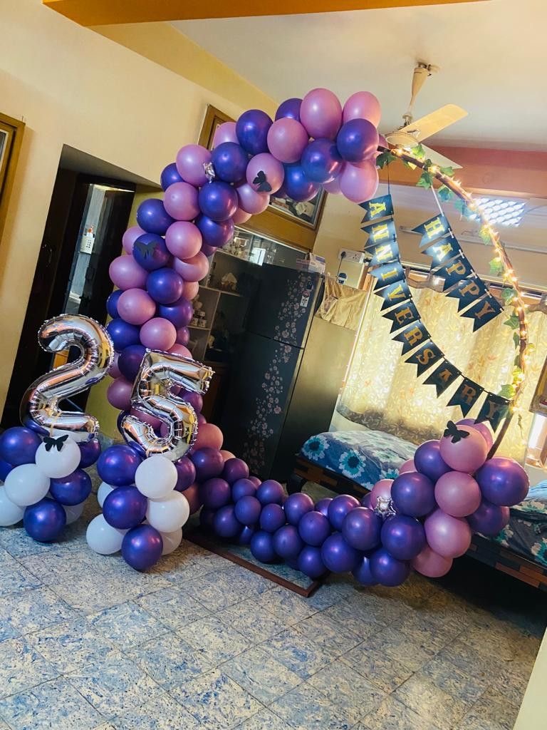 Purple and lavender balloon ring anniversary decoration with silver milestone number balloons and banner backdrop
