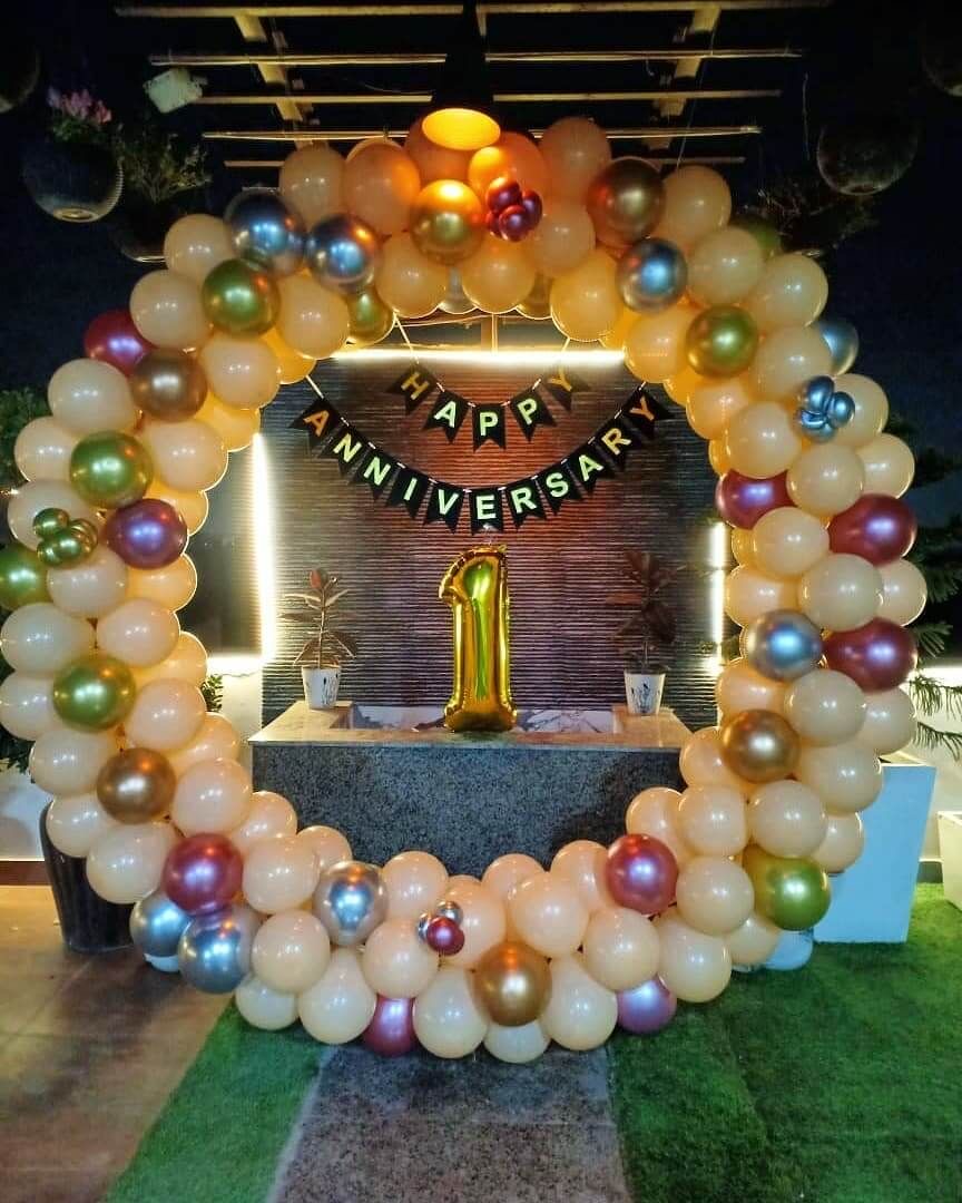 Golden balloon ring anniversary decoration with multicolor chrome balloons and LED number one prop on terrace