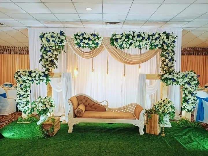 Elegant white and green garden theme wedding stage with floral frames and classic chaise lounge seating.