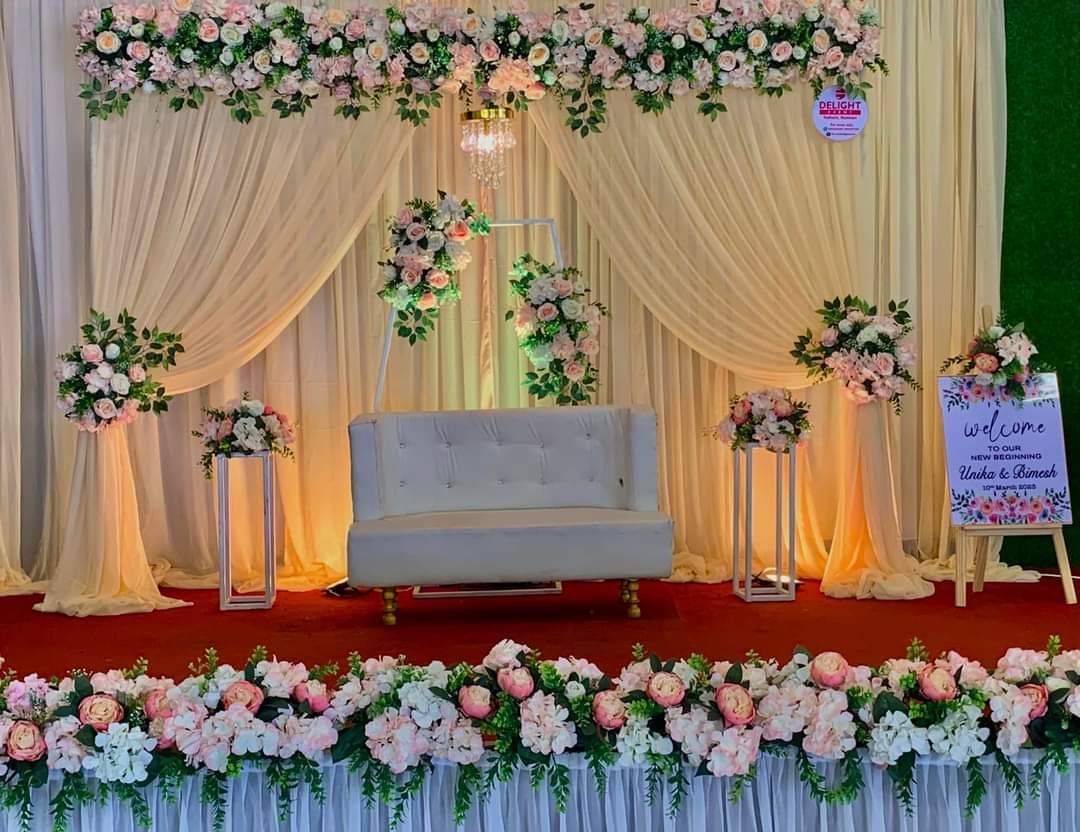 Elegant pastel floral arch wedding reception stage decoration with luxury sofa seating and warm ambient lighting setup