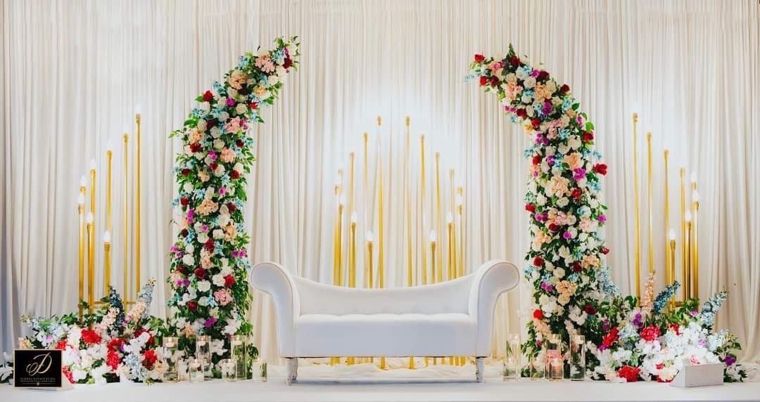 Elegant engagement stage decoration with yellow drape styling, floral top arrangements and contemporary brown sofa seating for reception events.
