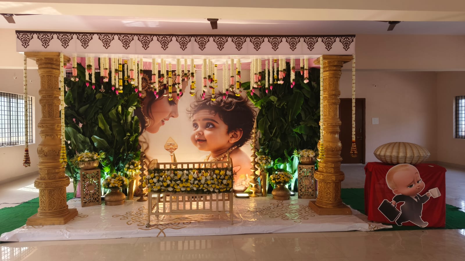 Cradle ceremony decoration with customized baby backdrop, floral cradle and traditional pillars.