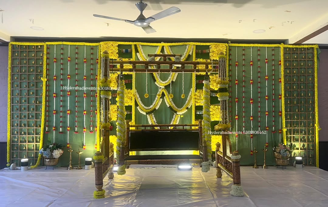 Seemantham cradle decoration with yellow floral backdrop, traditional swing and garlands in Hyderabad.