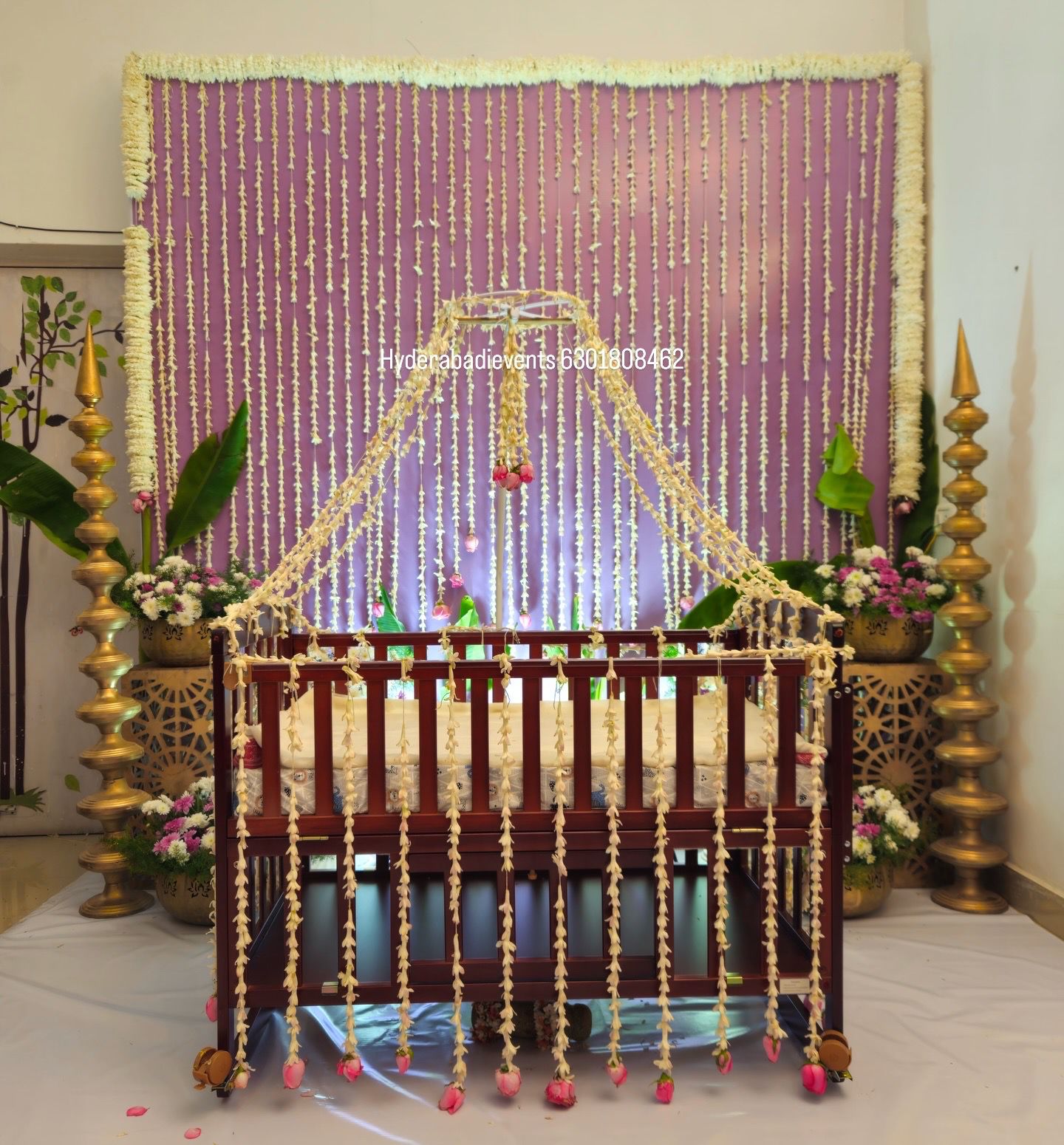 Premium cradle ceremony decoration with wooden cradle, jasmine garlands canopy and floral backdrop setup in Hyderabad.