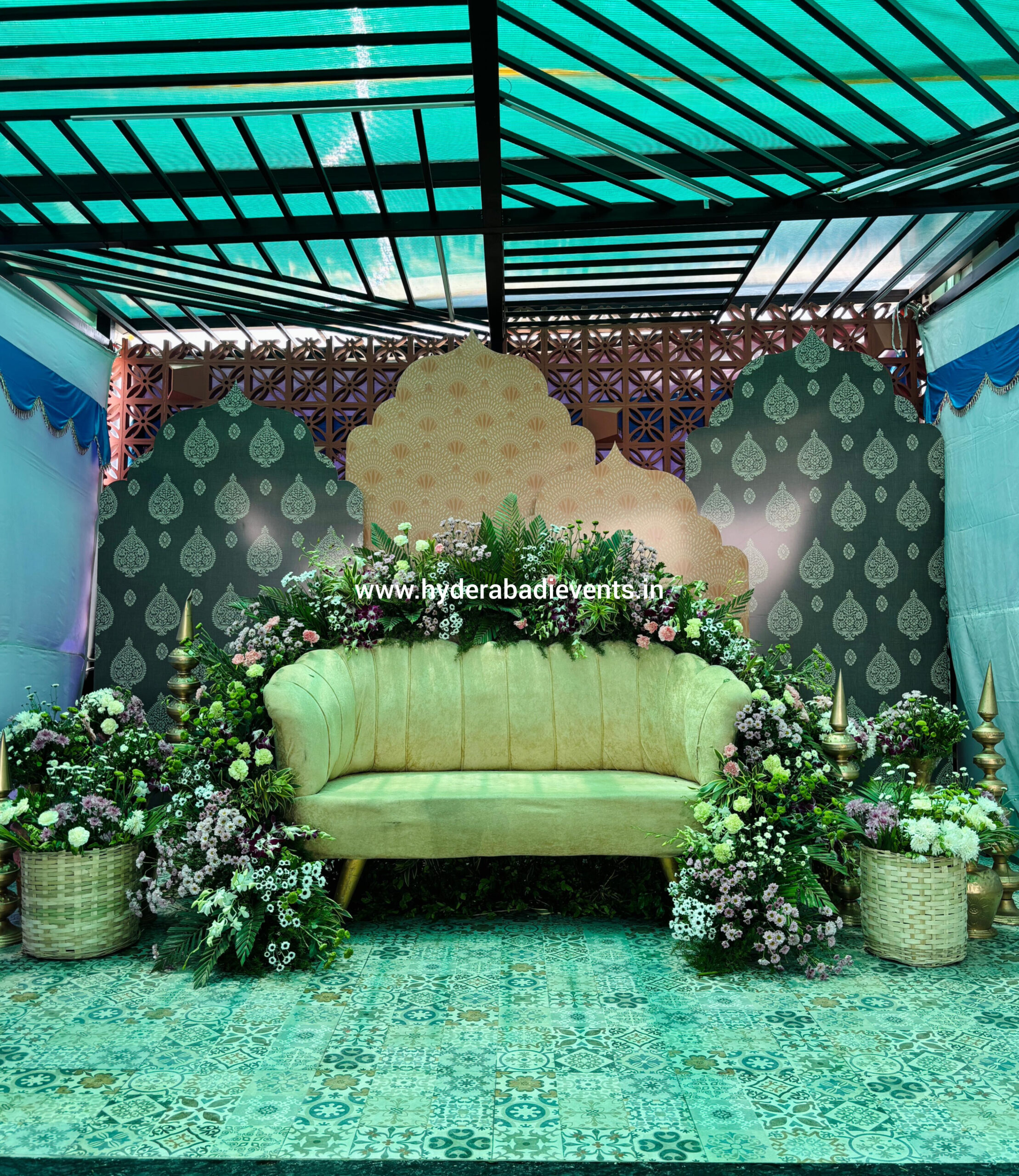 Mehendi function lounge setup with green theme sofa and floral decoration in Hyderabad.