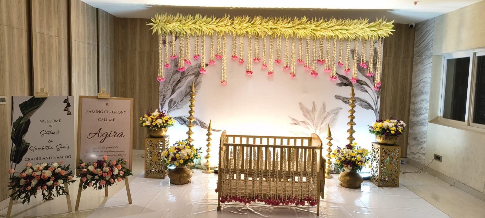 Naming ceremony cradle setup with welcome board, floral décor and traditional lighting in Hyderabad.