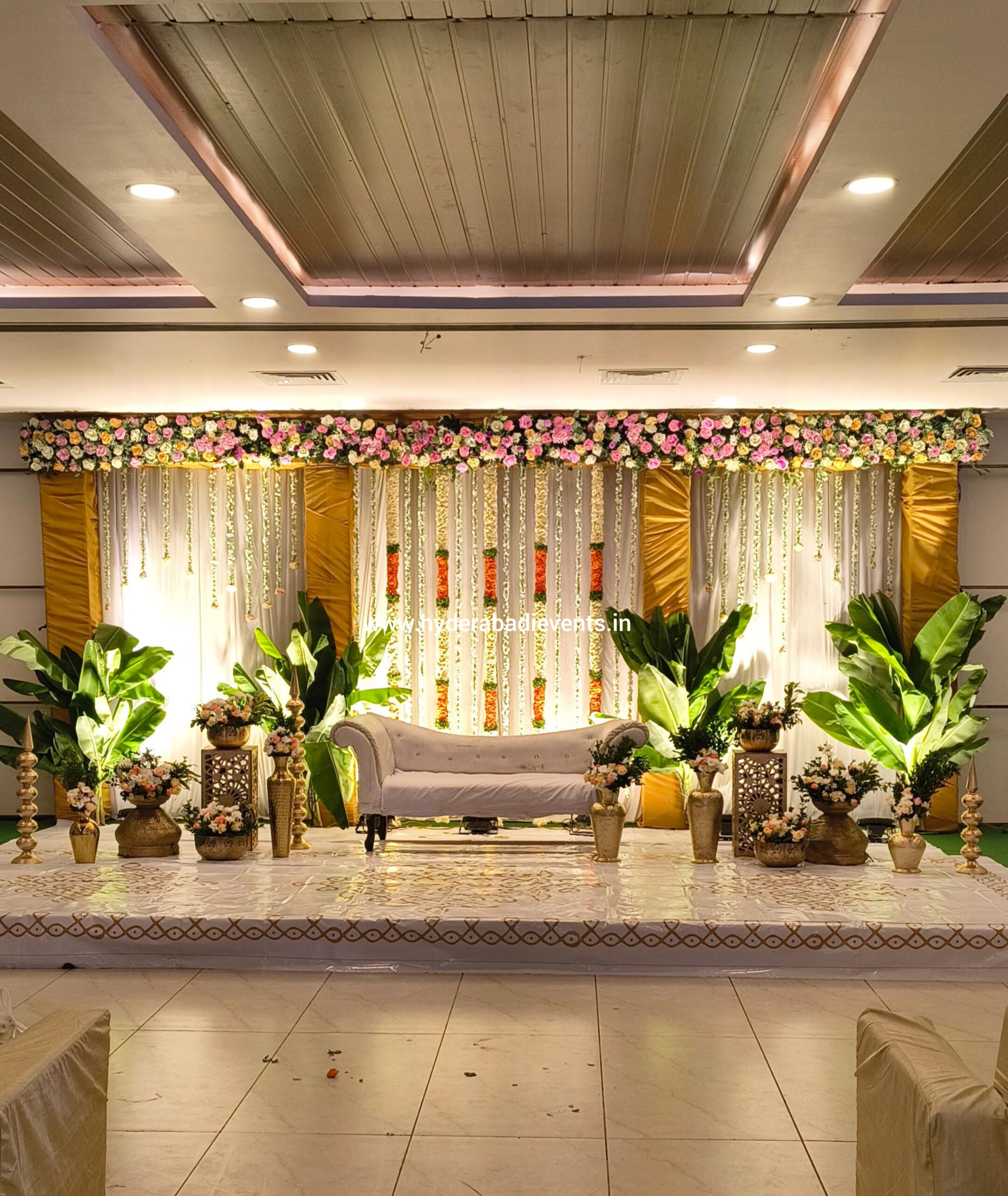Wedding stage decoration with floral backdrop, sofa seating and elegant lighting in Hyderabad.