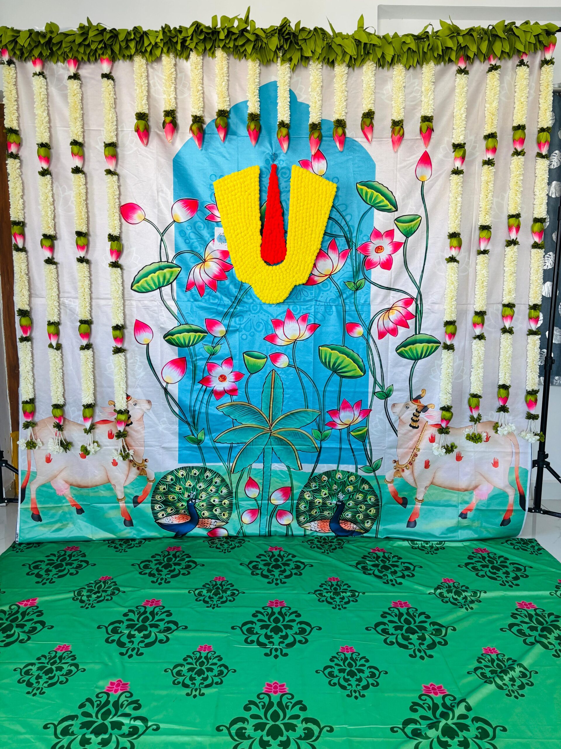 Traditional lotus floral backdrop rental with Vaishnav namam theme, jasmine hangings and banana leaf decoration for housewarming and puja events in Hyderabad.