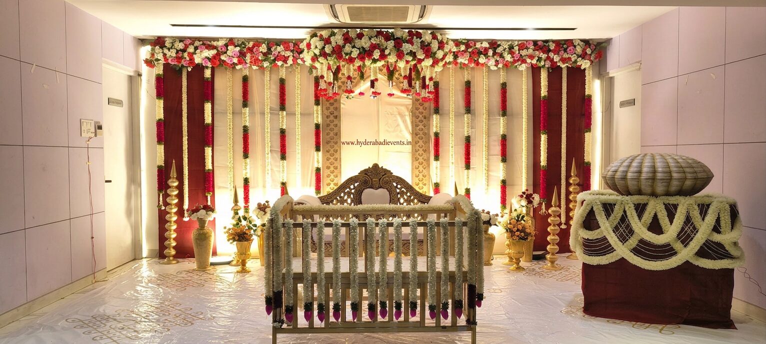 Luxury cradle ceremony decoration with floral backdrop, traditional cradle setup, jasmine garlands and elegant naming ceremony stage in Hyderabad.