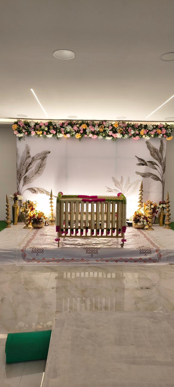Elegant floral cradle ceremony decoration with minimalist backdrop and flower arrangements