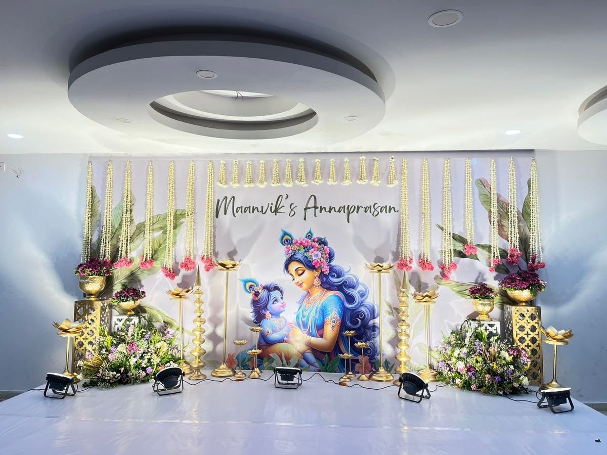 Radha Krishna themed Annaprasana stage decoration with floral garlands and traditional baby ceremony setup