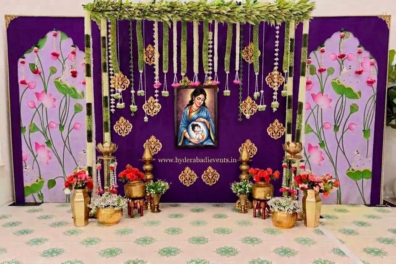 Royal peacock theme naming ceremony decoration with floral backdrop, peacock artwork, hanging jasmine garlands, fresh flowers, brass lamps, and elegant cradle ceremony stage decoration in Hyderabad.